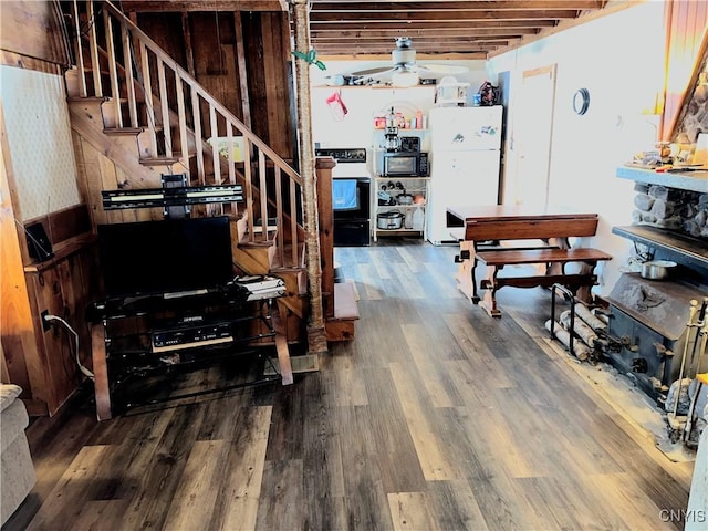 interior space featuring a wainscoted wall, ceiling fan, stairs, and wood finished floors