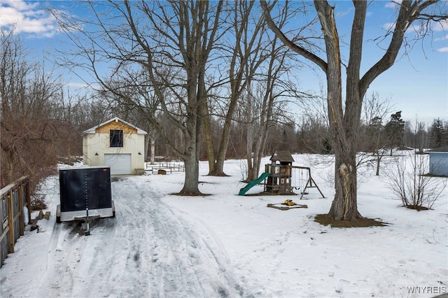 yard layered in snow featuring a garage, fence, and a playground