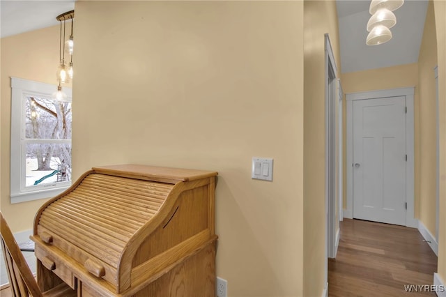 hallway with lofted ceiling, wood finished floors, and baseboards