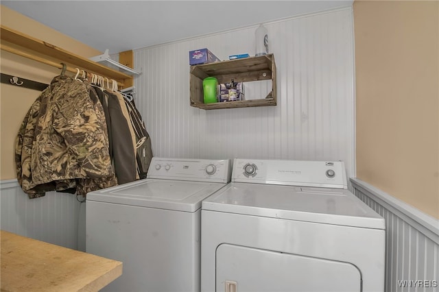 clothes washing area featuring washing machine and dryer, laundry area, and a wainscoted wall