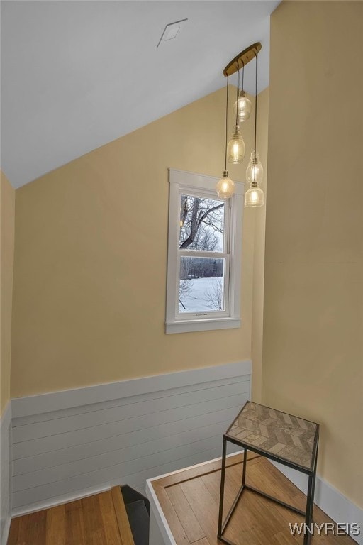 interior space with vaulted ceiling, wainscoting, and wood finished floors