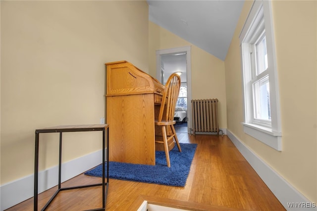 bedroom with radiator heating unit, baseboards, vaulted ceiling, and wood finished floors