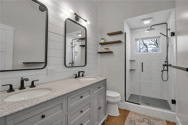 full bath with toilet, a shower stall, a sink, and wood finished floors