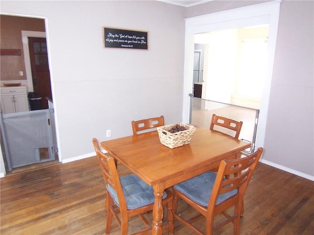 dining area featuring crown molding, baseboards, and wood finished floors