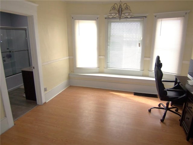 office with a chandelier, wood finished floors, visible vents, and baseboards