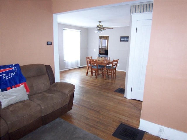 living area with visible vents, ceiling fan, baseboards, and wood finished floors