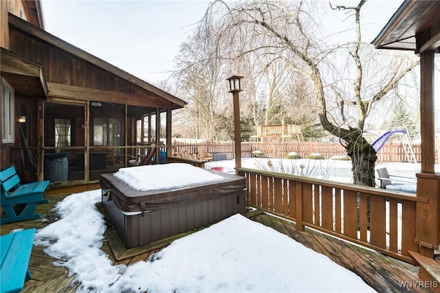 snow covered deck with fence, a sunroom, and a hot tub