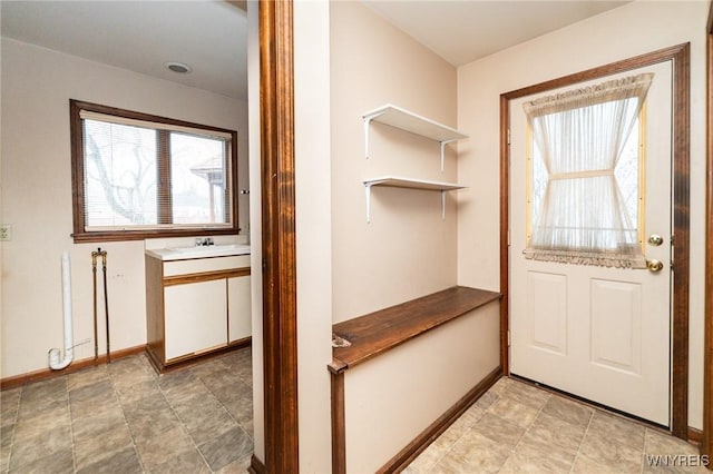 doorway to outside featuring baseboards and a sink