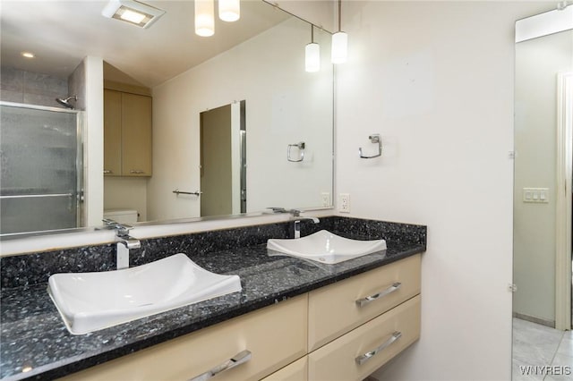 full bath featuring double vanity, a sink, toilet, and a shower stall