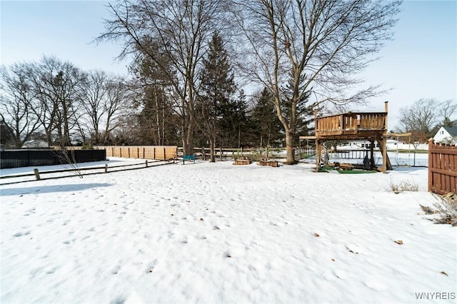 snowy yard with fence and a deck