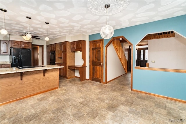 kitchen featuring a kitchen bar, pendant lighting, baseboards, and black appliances