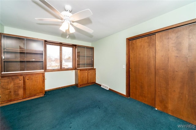 unfurnished bedroom featuring dark colored carpet, a closet, visible vents, ceiling fan, and baseboards