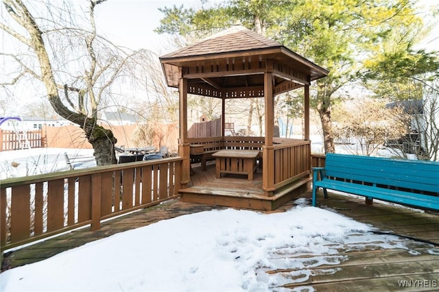 snow covered deck featuring a gazebo and fence