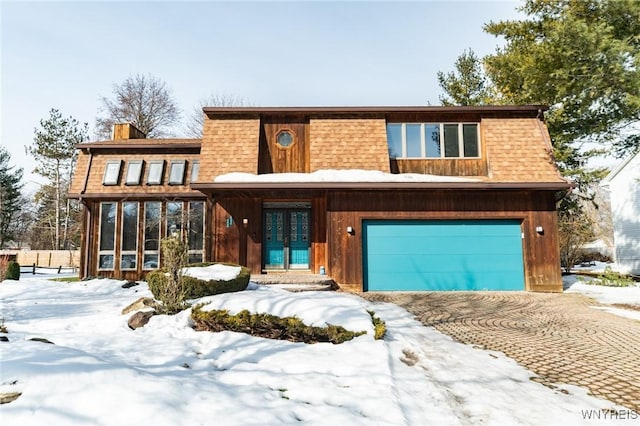 view of front of house featuring an attached garage, a sunroom, french doors, roof with shingles, and a chimney