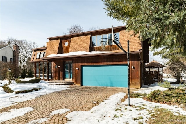 view of front of home featuring a garage, a sunroom, roof with shingles, and mansard roof