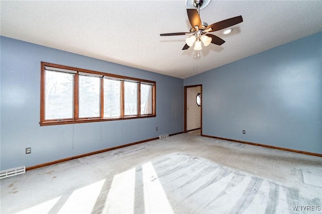 empty room featuring lofted ceiling, a textured ceiling, visible vents, and baseboards