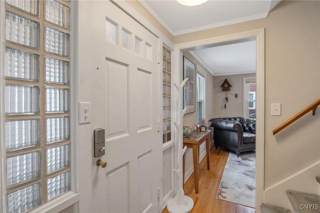 foyer entrance featuring light wood-type flooring, stairway, and ornamental molding