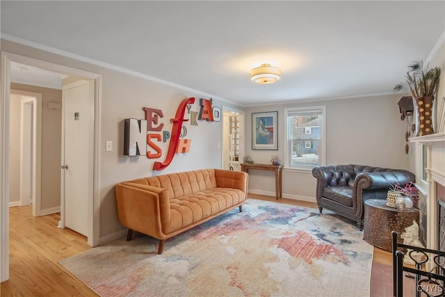 sitting room featuring light wood finished floors, a fireplace, baseboards, and crown molding