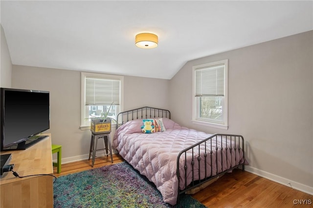 bedroom featuring lofted ceiling, baseboards, and wood finished floors