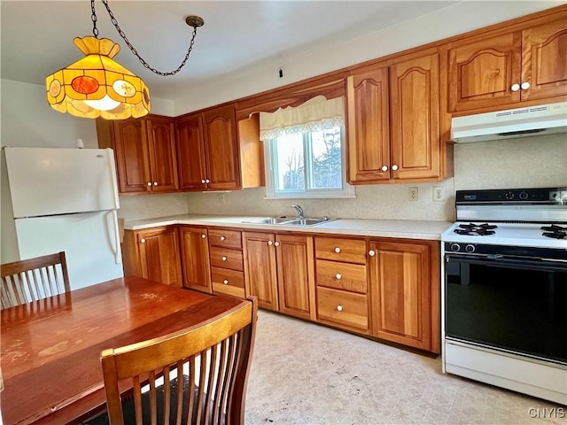 kitchen with electric stove, light countertops, freestanding refrigerator, a sink, and under cabinet range hood