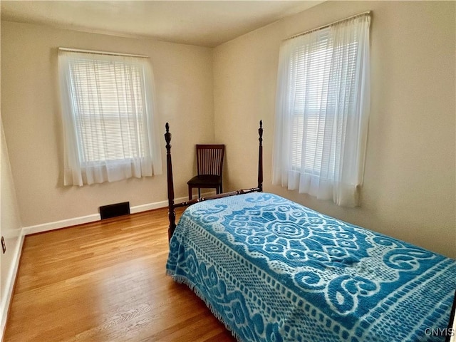 bedroom with visible vents, baseboards, and wood finished floors