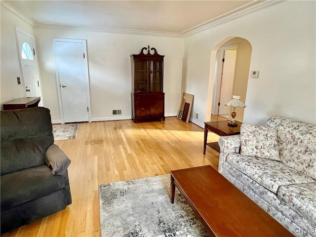 living room with baseboards, arched walkways, wood finished floors, and ornamental molding