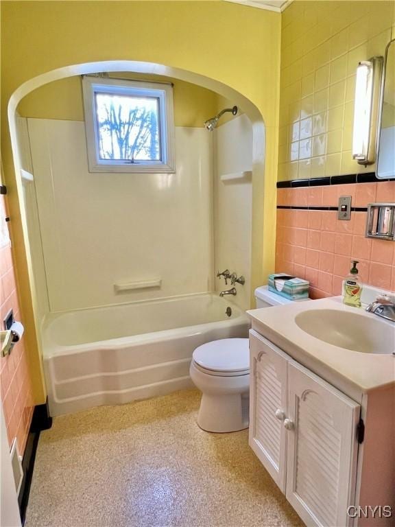 bathroom with toilet, vanity, shower / tub combination, and tile walls