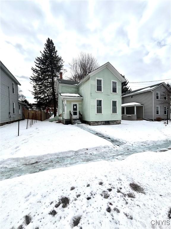 snow covered back of property featuring a garage and a chimney