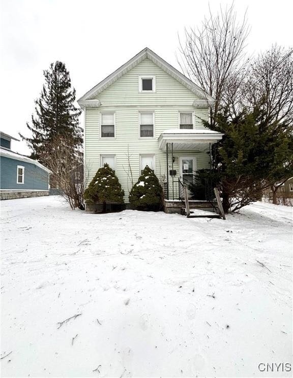 snow covered back of property featuring a porch