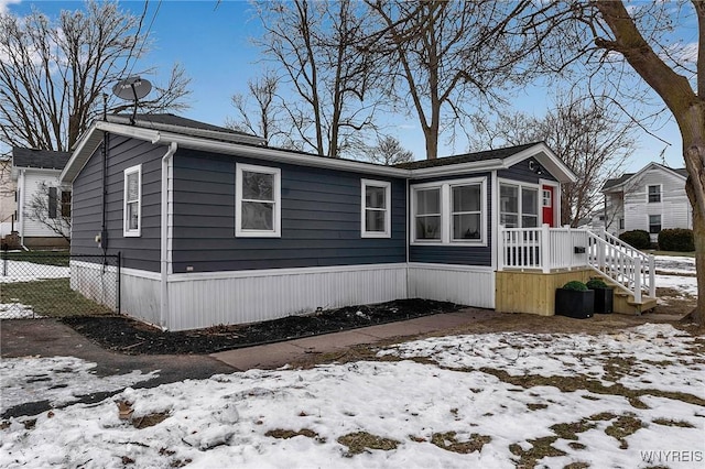 snow covered property featuring a sunroom and fence