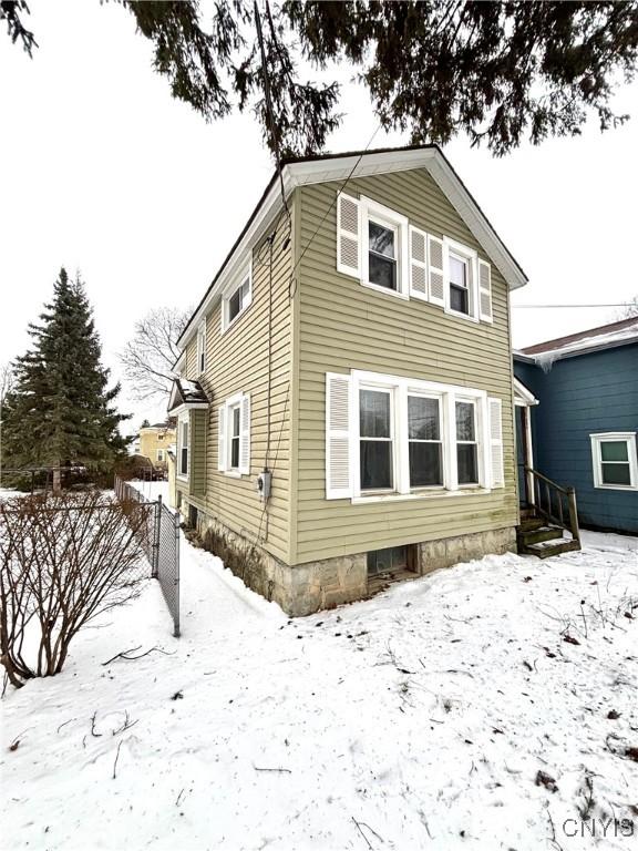 snow covered rear of property with fence