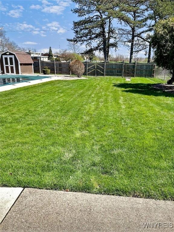 view of yard with a fenced backyard, an outdoor structure, and a storage unit