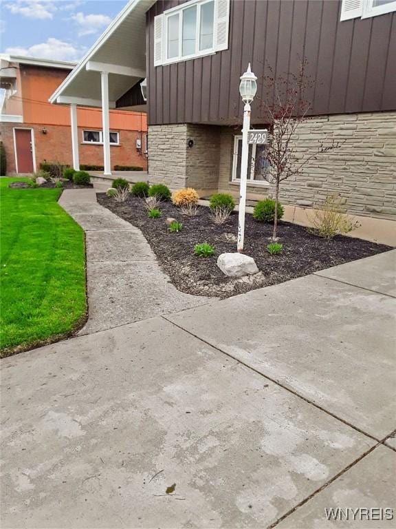 exterior space with board and batten siding, stone siding, and a lawn