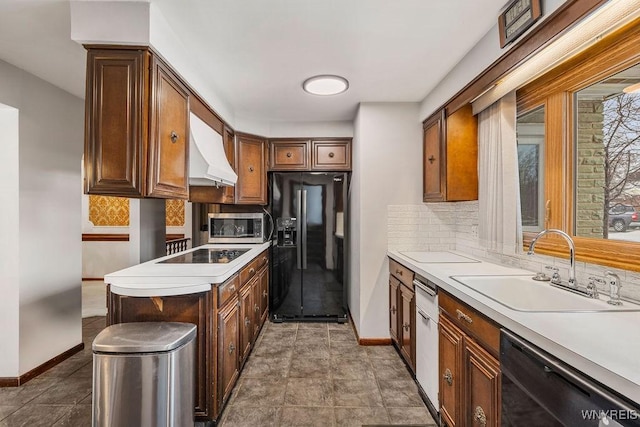 kitchen with a sink, light countertops, backsplash, black appliances, and custom range hood