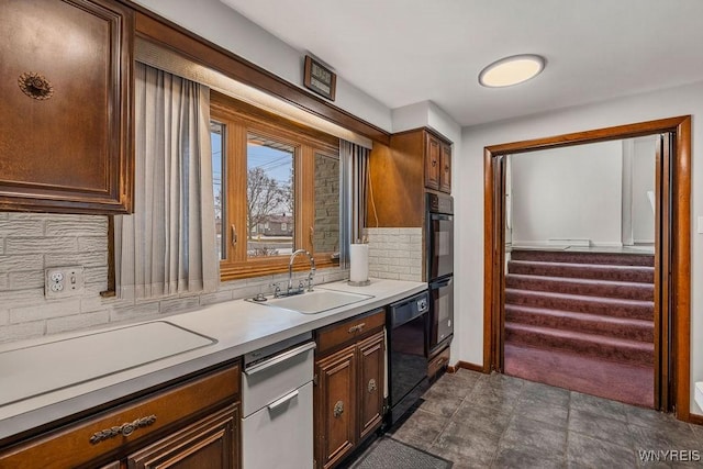 kitchen featuring light countertops, backsplash, a sink, black appliances, and baseboards