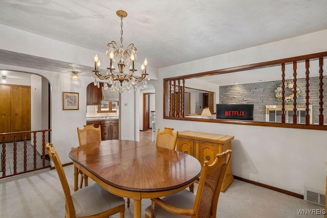 dining space featuring light carpet, an inviting chandelier, visible vents, and arched walkways