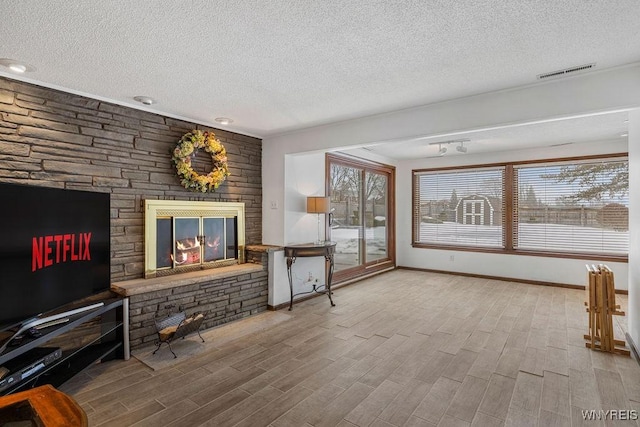 living area with a textured ceiling, a fireplace, wood finished floors, and visible vents