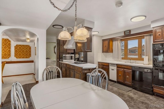 kitchen featuring arched walkways, a sink, light countertops, decorative backsplash, and black appliances