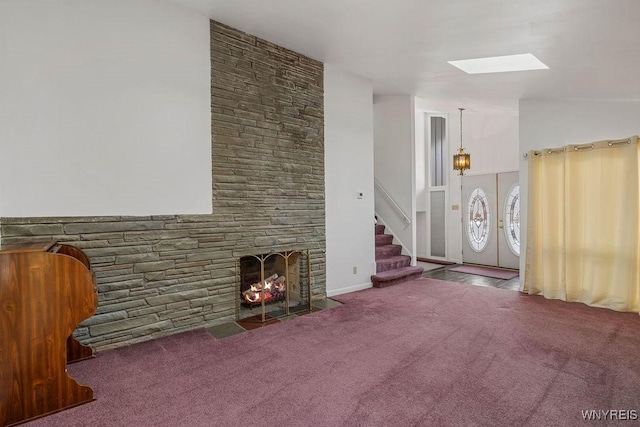 unfurnished living room featuring stairs, a stone fireplace, and carpet flooring