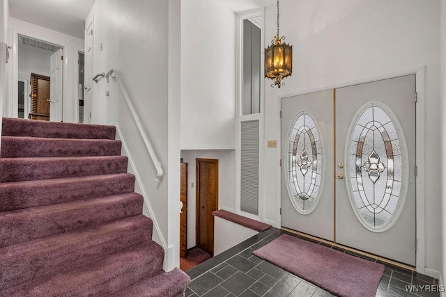 foyer entrance featuring french doors, stairway, tile patterned floors, and a notable chandelier