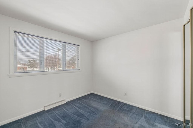 spare room featuring baseboard heating, dark carpet, and baseboards