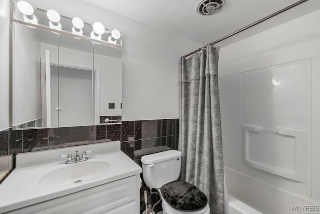 bathroom with toilet, visible vents, vanity, tile walls, and shower / bath combo