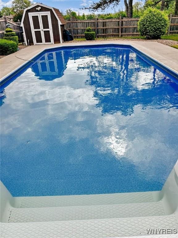 view of pool with an outbuilding, a storage unit, a fenced backyard, and a fenced in pool