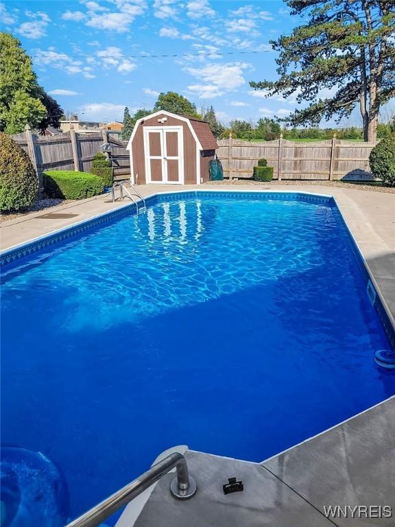 view of pool featuring a fenced in pool, an outbuilding, a fenced backyard, and a shed