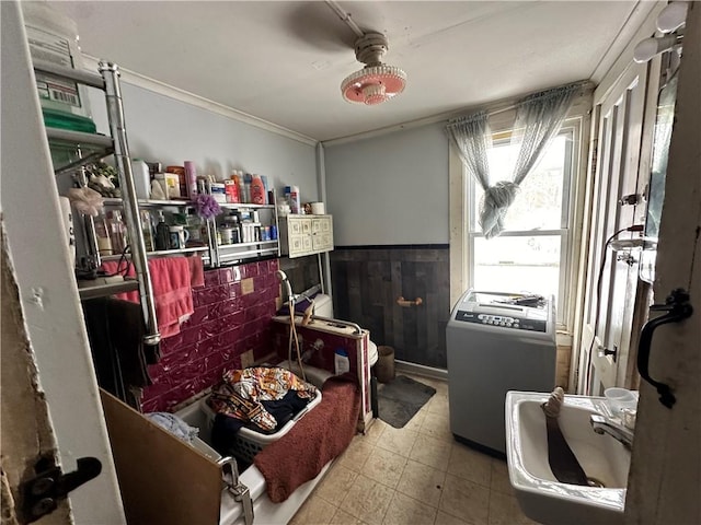 interior space featuring a wainscoted wall, washer / clothes dryer, a ceiling fan, and crown molding