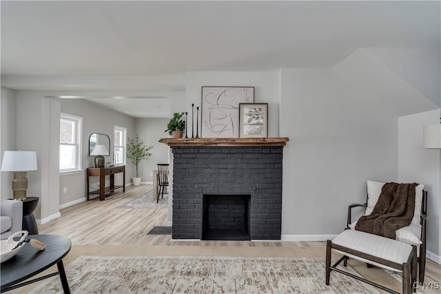 living area featuring a fireplace, wood finished floors, and baseboards