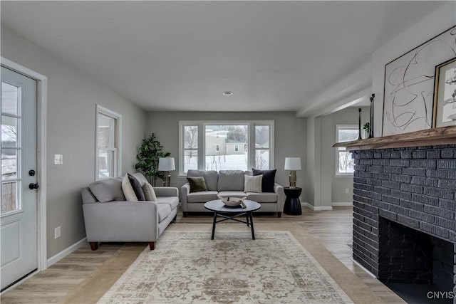 living room featuring light wood finished floors, a fireplace, and baseboards