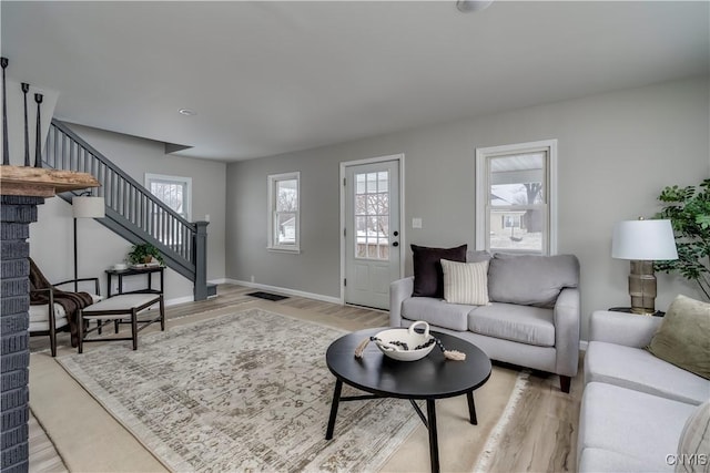 living room featuring baseboards, stairway, and light wood-style floors