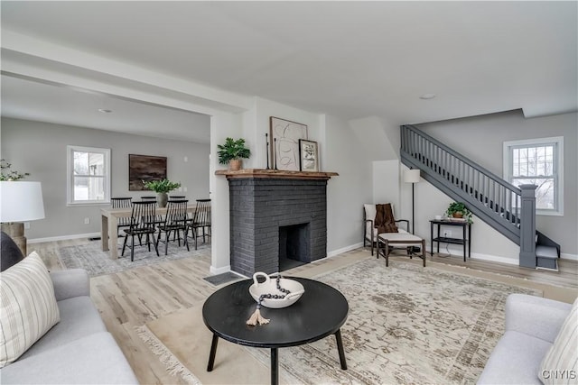 living room with a wealth of natural light, a fireplace, stairway, and wood finished floors