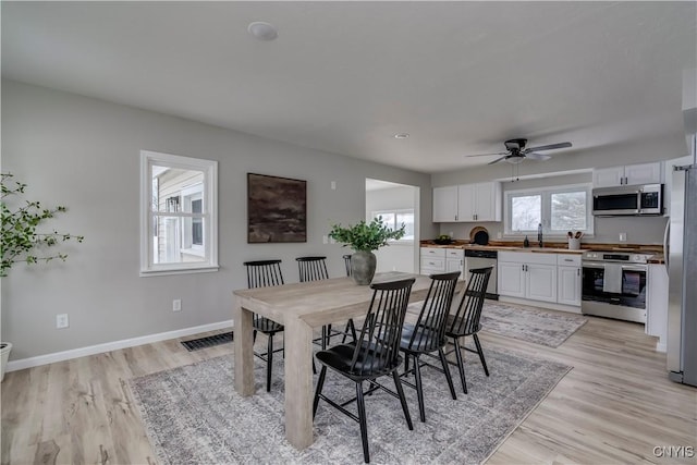 dining room with ceiling fan, light wood finished floors, visible vents, and baseboards